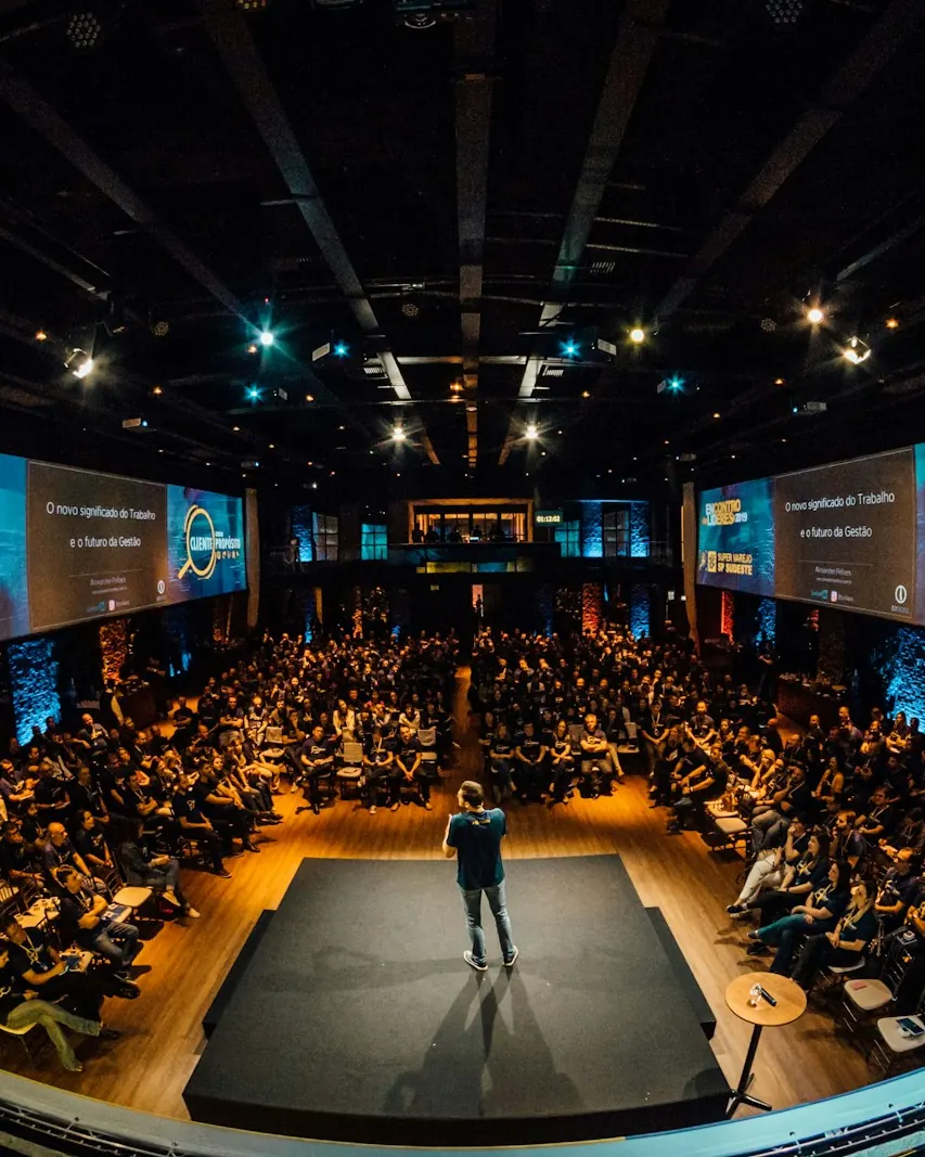 A speaker on stage in front of a large conference audience